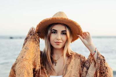 Portrait of young woman wearing hat at beach