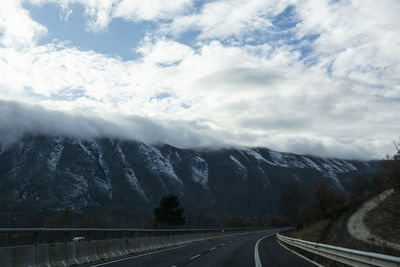 Road leading towards snowcapped mountains against sky