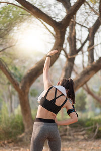 Midsection of woman standing by tree on land