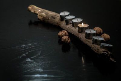 Close-up of tea light on wood by walnuts