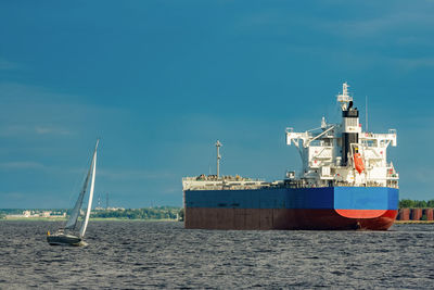 Sailboat moored on beach against blue sky