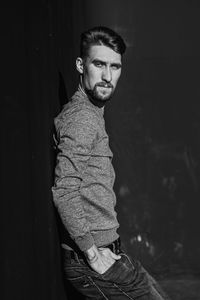 Portrait of young man standing against wall