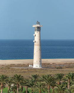 Lighthouse by sea against sky