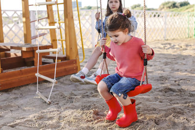 Full length of smiling girl sitting on land