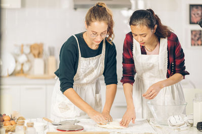 Young woman looking away while standing in kitchen