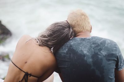 Rear view of couple sitting against sea