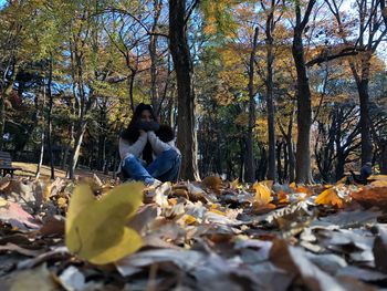 Woman sitting on autumn leaves in forest