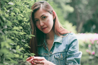 Portrait of beautiful young woman against plants