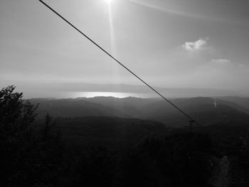 Overhead cable car over mountains against sky