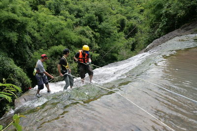 People climbing on waterfall in forest