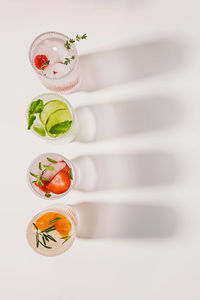 Top view of ribbed glasses with lemonade or infused water with different flavors on the white table