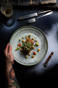 Midsection of person holding food in plate on table