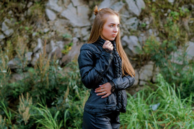 Young woman wearing black warm clothing against rock formation