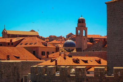 View of bell tower in city against clear blue sky