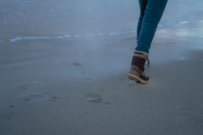 Feet run along the beach leaving footprints in the sand, part of the human body