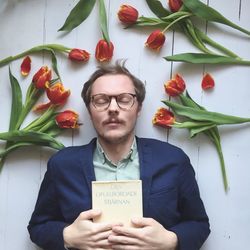 Close-up of man with book amidst flowers sleeping on floor