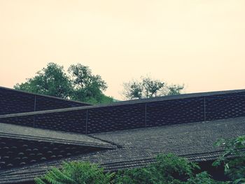 Low angle view of trees and building against sky