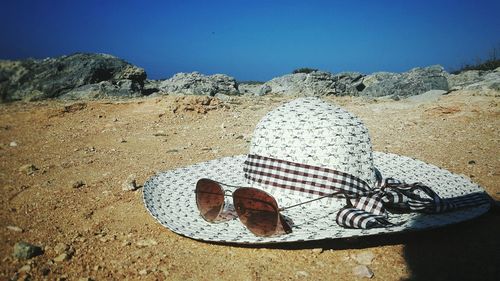 Close-up of hat and sunglasses on sand at beach