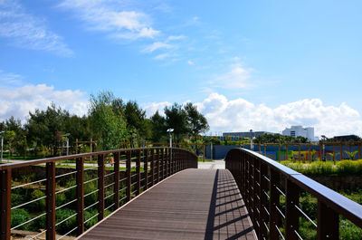 Footbridge against cloudy sky