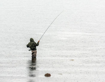 Rear view of man fishing in water