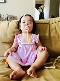 Cute baby girl sitting on bed at home