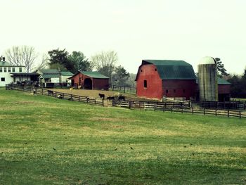 Barn on field by buildings against sky