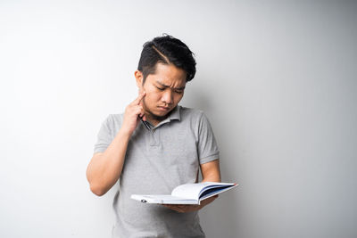 Young man looking away against white background