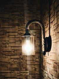 Low angle view of illuminated light bulb against wall