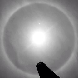 Low angle view of sun shining through clouds