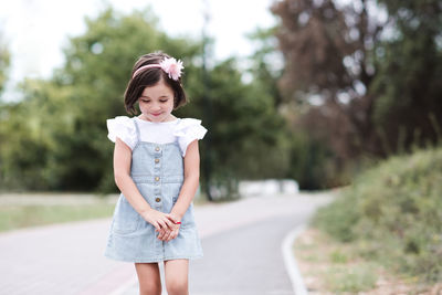 Smiling child 3-4 year old wearing denim dress outdoors. walking in park.