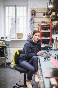 Portrait of mature female technician sitting in electronics store