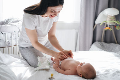 Mother and baby boy communicating after sleep. caucasian child changing diaper at home. adorable
