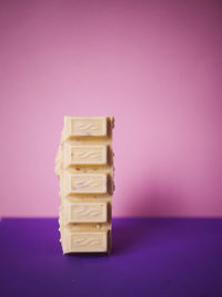 Close-up of stack on table against pink background