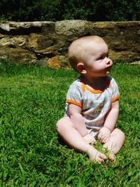 Full length of baby boy sitting on grassy field at park