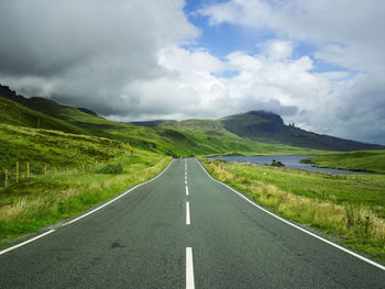 Road amidst green landscape against sky