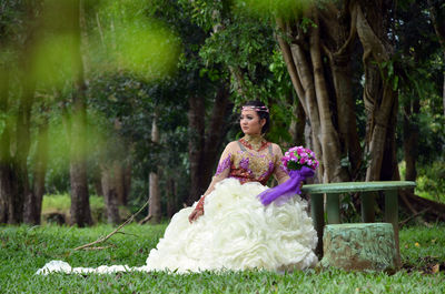 Bride sitting by table on field