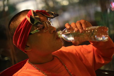 Close-up of mid adult man drinking water while sitting on chair at night