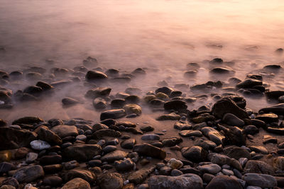 Rocks at beach during sunset