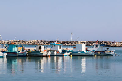 Sailboats moored at harbor against clear blue sky