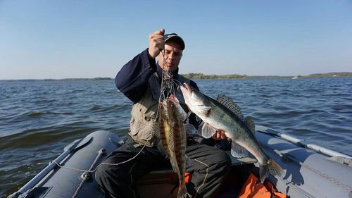 Full length of man holding fish in sea against sky