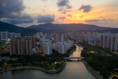 River amidst buildings in city against sky during sunset