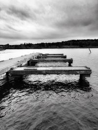 Pier in sea against cloudy sky