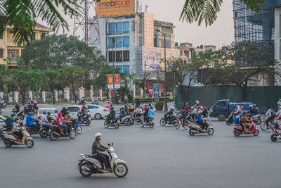 People riding bicycles on road by buildings in city