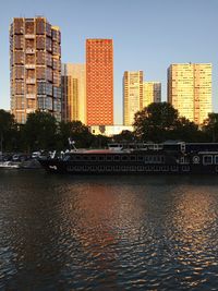 Buildings by river against clear sky in city