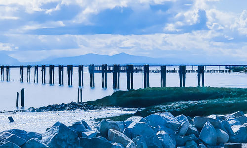 Wooden posts in sea against sky