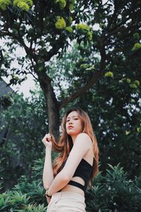 Portrait of young woman standing against trees