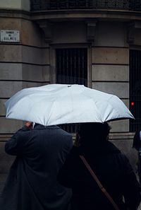 Rear view of man with umbrella walking on rainy day