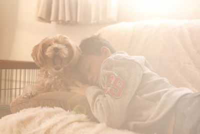 Boy sleeping by dog on sofa at home