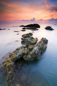 High angle view of rocks in sea against sky during sunset