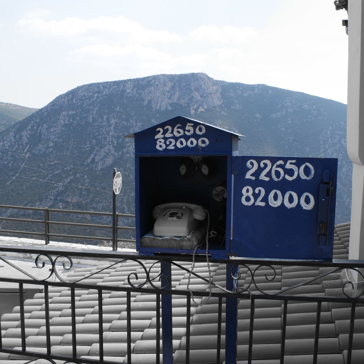 mountain, text, communication, day, sky, outdoors, nature, no people, mountain range, telephone, architecture, western script, sign, technology, safety, railing, cloud - sky, scenics - nature, barrier, fence